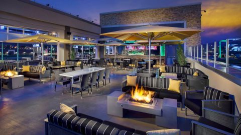 Outdoor patio area of TopGolf, Utah. Area includes seating, fireplaces, and umbrellas for shade. 