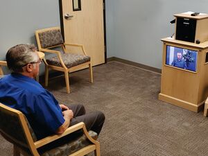 A man watches a family video in the family story room at the Riverton family history center.