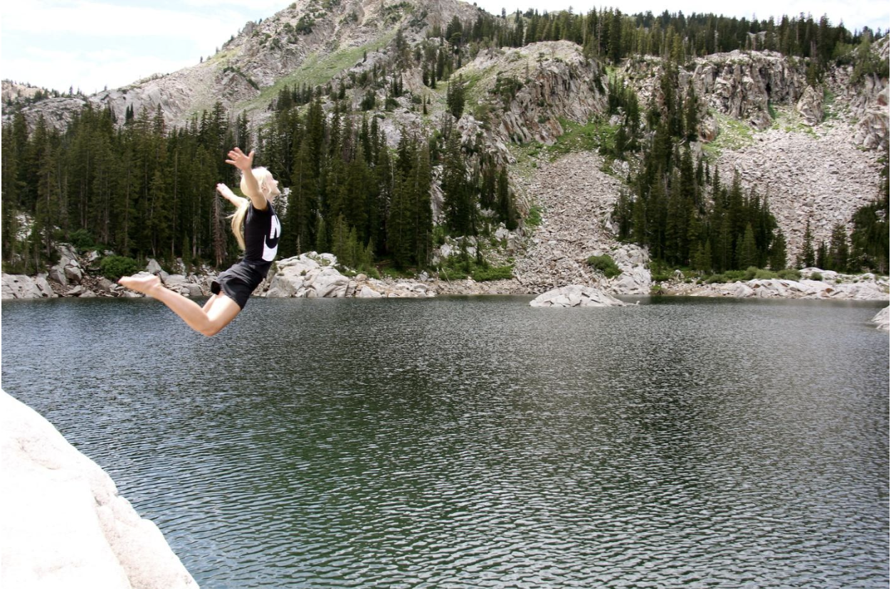Woman just jumping off the cliff, high above the water