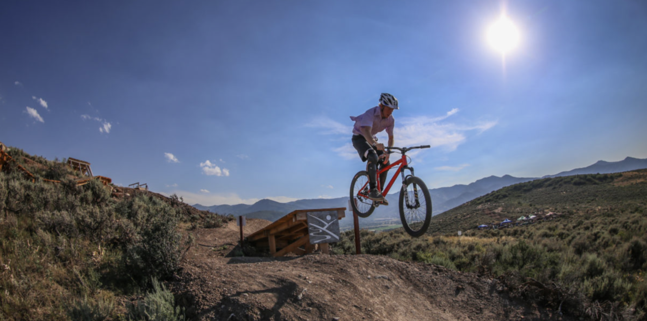 A cyclist on a mountain bike jumps off a ramp at Trailside Bike Park (Park City, Utah)