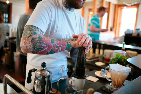 Barista working the coffee press.