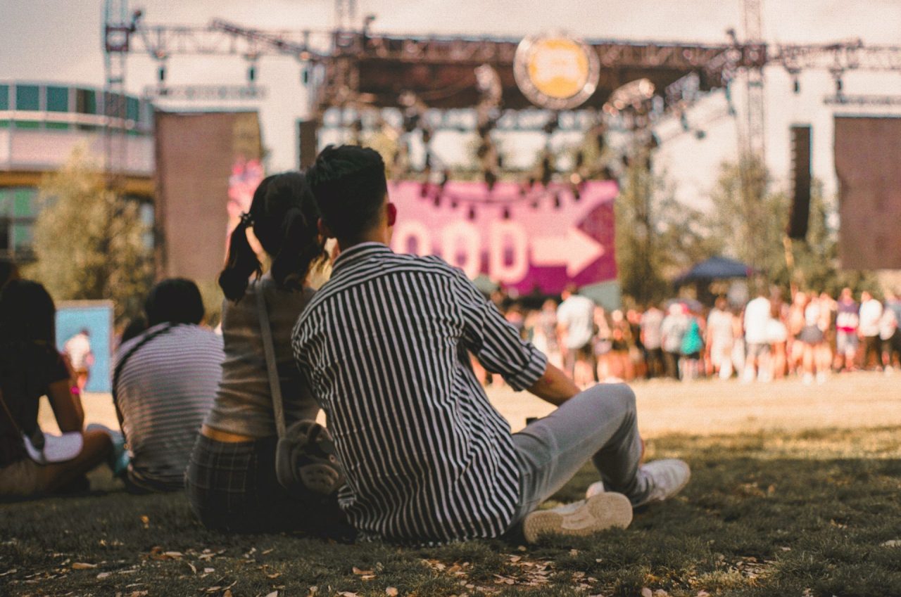 Couple sitting in the grass watching a concert