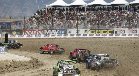 Off-road racing trucks competing at Utah Motorsports Campus in front of a packed grandstand crowd.