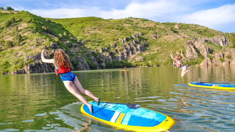 Friends jumping off paddleboards into the water at Causey Reservoir, a top destination for summer outdoor activities near Salt Lake City in the Wasatch Mountains.