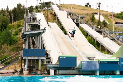 A freestyle skier performing a Cork 7 Iron-cross backflip off a ramp into water at the Utah Olympic Park in Park City during the summer season.