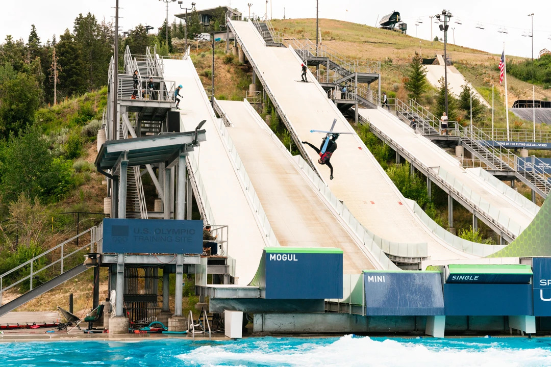 A freestyle skier performing a Cork 7 Iron-cross backflip off a ramp into water at the Utah Olympic Park in Park City during the summer season.